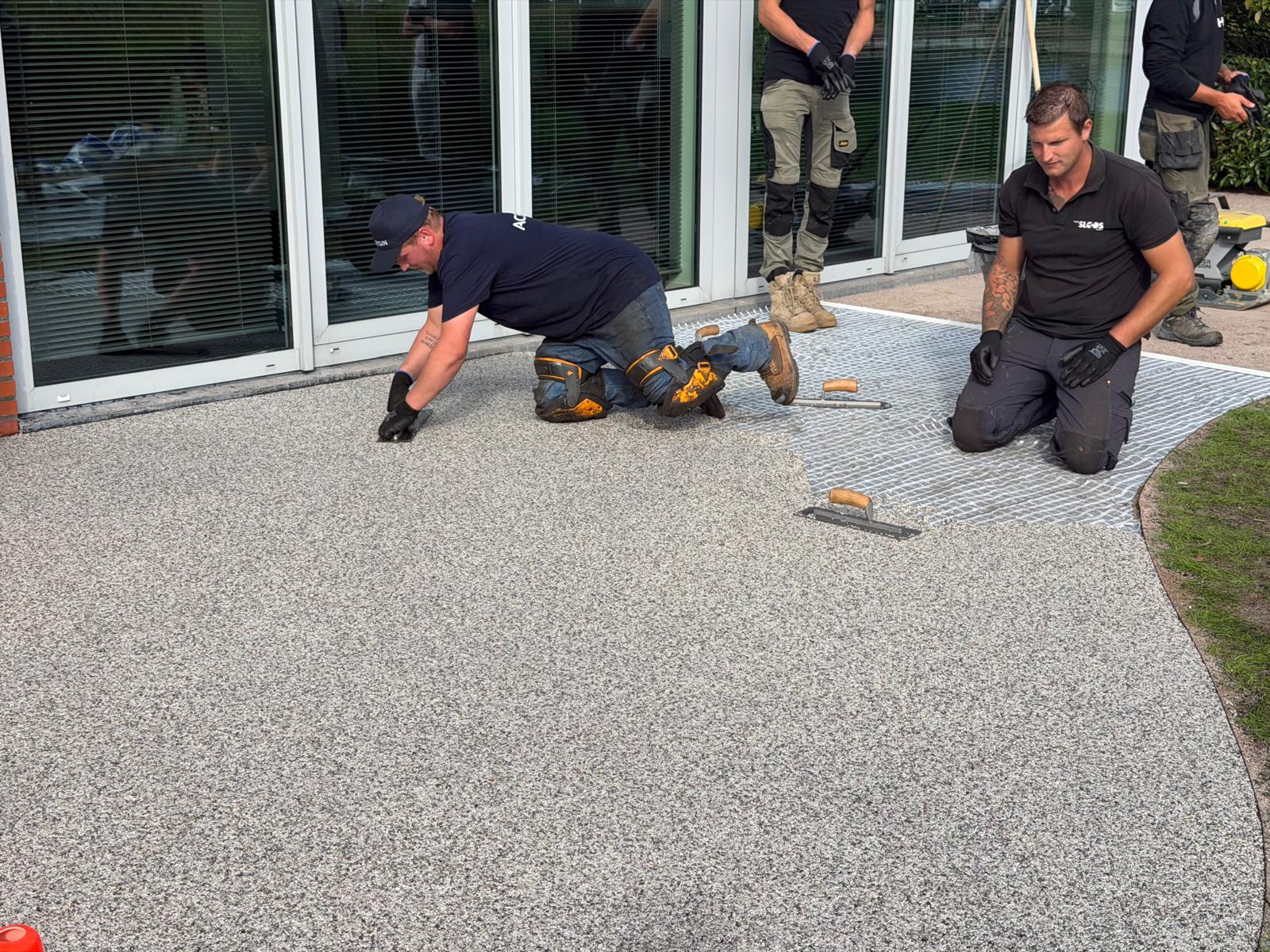 Vakmensen van Step Stones brengen harsgebonden grind aan bij een terras